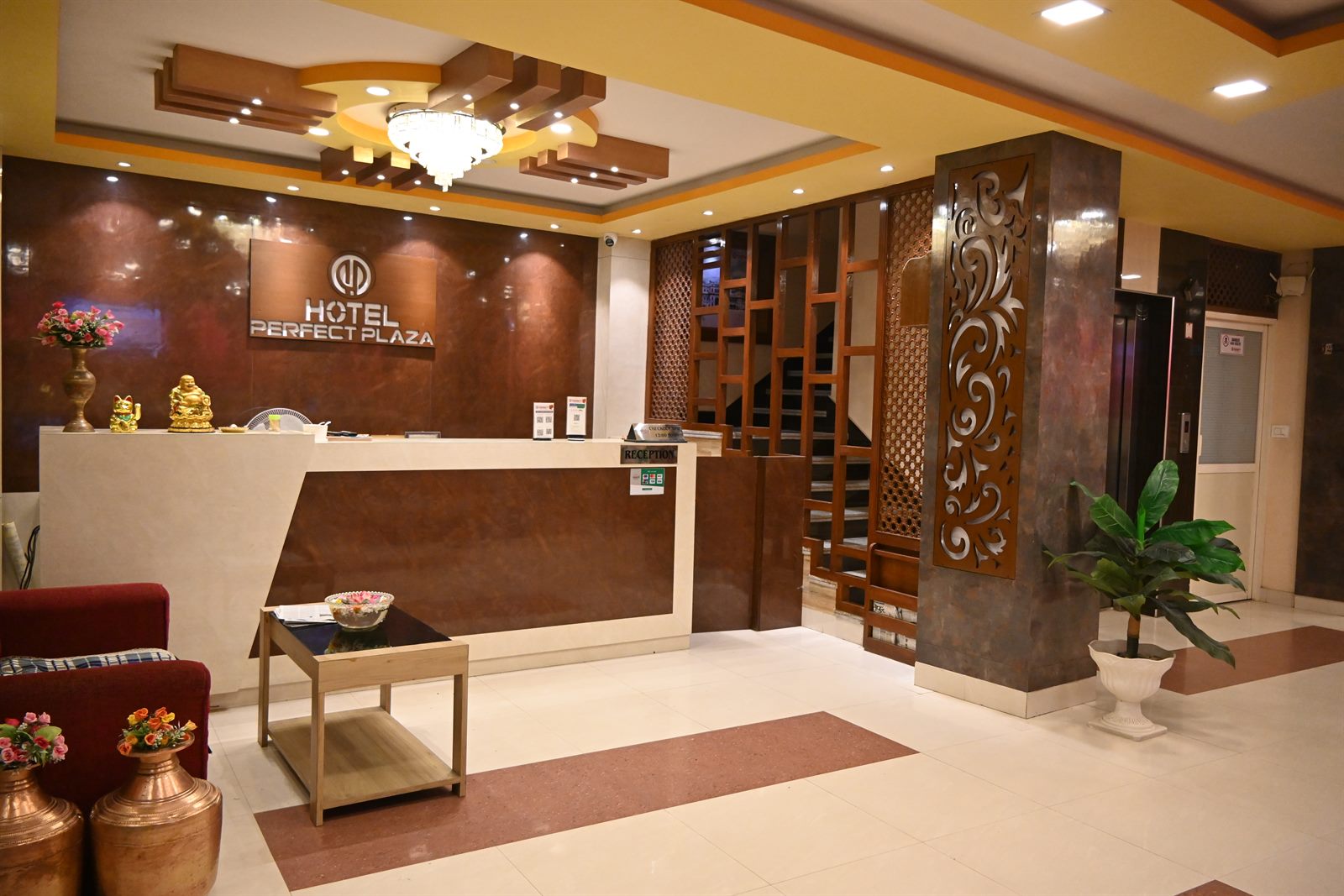 The reception desk at Hotel Perfect Plaza, with the hotel's own logo on the wall behind