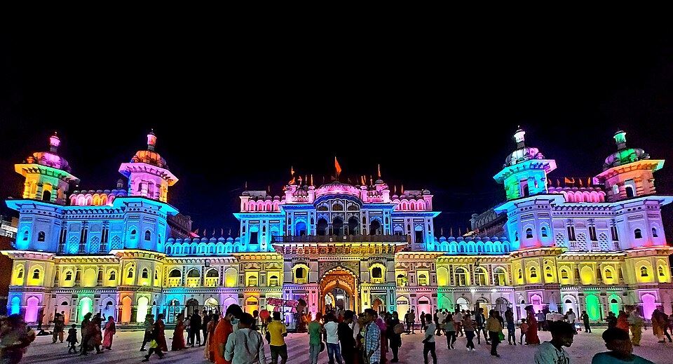 The Janaki Mandir lit up in colour at night, with crowds in the courtyard