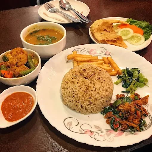 A set meal: rice with greens and a spiced stir-fry, with soup, a vegetable curry, chutney and papad